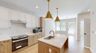 Located at 19020 Potts Park Lane in Davidson, NC, this thoughtfully designed one-bedroom, one-bathroom residence offers an efficient and modern living experience on a single floor. The open-concept layout seamlessly connects the kitchen, dining, and living areas, creating a bright and cohesive space filled with natural light from large windows.

The kitchen is a standout feature, showcasing a two-tone design with white upper cabinetry and warm natural wood lower cabinets, complemented by quartz countertops and a white tile backsplash. A central island with an undermount sink and a brushed gold faucet serves as both a functional workspace and a focal point. Striking gold pendant lights hang overhead, adding a touch of elegance. Stainless steel appliances, including a French door refrigerator and a range, complete this well-appointed kitchen.

The bedroom is a calm retreat, featuring light wood flooring, neutral walls, and dual windows that invite ample natural light. The bathroom is equipped with accessibility features, including grab bars near the toilet and a tiled walk-in shower, combining practicality with clean design. Additional highlights include a dedicated laundry area, a closet for storage, and a private balcony. Light wood flooring flows throughout, tying the entire space together with warmth and consistency.