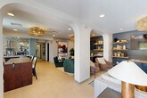 Located at 1070 Lois Ln in Harrisonburg, VA, this well-appointed single-floor amenity space offers a thoughtfully curated environment designed for both socializing and relaxation. The layout encompasses a living room, den, dining room, hallway, and multiple additional rooms, all finished with a cohesive modern aesthetic.

The central lounge area is anchored by elegant arched architectural details, open shelving with blue shiplap accent walls, and layered pendant lighting including eye-catching woven and sputnik-style fixtures. A built-in media console and plush seating arrangements create an inviting communal atmosphere, complemented by bold artwork and lush greenery.

The dining room is bathed in natural light through large windows offering outdoor views, and features multiple seating tables with upholstered chairs framed by linen drapes. An adjacent high-top dining table adds casual dining flexibility.

A dedicated game room serves as an entertainment hub, equipped with a ping-pong table and foosball table. Sliding glass doors open directly to an outdoor terrace, flooding the space with natural light and scenic views of the surrounding landscape.

A quieter sitting room, appointed with textured accent wallpaper, a sputnik chandelier, and curved lounge chairs, provides a more intimate retreat. Throughout, light flooring, recessed lighting, and neutral tones tie each area together into a cohesive, welcoming space.