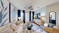 Located at 3200 Meadow Gate Ln in Davenport, FL, this well-appointed single-floor residence offers a thoughtfully designed layout that maximizes every inch of its space. The open-concept kitchen and living area serves as the heart of the home, featuring crisp white shaker cabinetry, quartz countertops, a bold blue island with seating, stainless steel appliances, a geometric tile backsplash, and pendant lighting with matte black hardware accents. Hardwood-style flooring flows throughout, tying the spaces together seamlessly. The living room is bright and inviting, with large windows dressed in navy curtains that allow natural light to filter in, complemented by a ceiling fan overhead. The bedroom offers a comfortable retreat, highlighted by a striking botanical wallpaper accent wall, a ceiling fan, and a window with outdoor views. The full bathroom features white cabinetry, a quartz vanity, and a clean, minimalist layout with ample room to move. A dedicated laundry room houses a full-size washer and dryer with built-in shelving above. A closet provides additional storage. The overall aesthetic is coastal and contemporary, with a cohesive blue-and-white color palette that lends the space a fresh, relaxed ambiance.