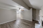 This two-story home in Houston, Texas offers a well-organized layout across two levels, combining functional design with comfortable living spaces. The main level hosts the kitchen and living area, while the upper level accommodates the bedrooms and bathrooms.

The living room is a standout space, featuring vaulted ceilings, a wood-style fireplace with a white tile surround and classic mantel, and durable hardwood-style flooring. A ceiling fan adds to the room's comfort, and the open sightlines create a welcoming atmosphere.

The galley-style kitchen is efficiently designed, with warm wood cabinetry lining both sides, granite-look countertops, a single-basin sink with a matte black faucet, and black appliances including a refrigerator, stove, microwave, and dishwasher. Light wood-style flooring and overhead lighting complete the space.

Each bedroom features plush carpeting, a ceiling fan, and natural light from windows. The generously sized primary bedroom includes direct access to an en-suite bathroom with a wood-toned vanity, large mirror, and a tub-shower combination finished in crisp white tile. The second bathroom is similarly appointed.

Both closets are walk-in style with built-in shelving and hanging rods, offering excellent storage. The home's neutral color palette and consistent finishes throughout create a cohesive and move-in-ready environment.