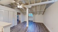 Located at 601 Bridge St in Danville, Virginia, this 2-bedroom, 1-bathroom residence showcases a distinctive architectural character that sets it apart. The open-concept living, dining, and kitchen area is the heart of the home, highlighted by dramatic exposed beam ceilings with white-painted wood planking, large skylights that flood the space with natural light, and durable wood-look flooring throughout. A ceiling fan and visible ductwork add an industrial-loft aesthetic to the airy main living area, which also features a central support column as a structural design element.

The kitchen is well-appointed with warm wood cabinetry, white countertops, stainless steel appliances including an electric range, microwave, and refrigerator, and a double-basin sink set into a peninsula that opens to the living space. Pendant lighting above adds a polished touch.

The primary bedroom is generously sized and benefits from the same soaring ceiling design and natural skylight illumination. The second bedroom offers additional flexibility. Four closets provide ample storage throughout the unit, complemented by an in-unit laundry area for added convenience.

The bathroom features a walk-in shower with tiled surround, a built-in bench, and a handheld showerhead. Wood-look flooring continues throughout, tying the space together cohesively.