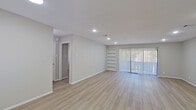 This well-appointed single-floor residence offers a clean, contemporary aesthetic throughout, with light neutral tones, recessed lighting, and durable wood-look vinyl plank flooring that flows seamlessly from room to room. The open-concept living area is spacious and airy, anchored by a large sliding glass door fitted with vertical blinds that invite an abundance of natural light and provide outdoor access. A set of built-in shelving units adds both function and character to the living space.

The kitchen is thoughtfully designed with white shaker-style cabinetry, granite countertops, a center island with a sink, and stainless steel appliances including a refrigerator, range, and microwave. A white subway tile backsplash adds a classic touch, while a stacked washer and dryer unit is conveniently tucked just off the kitchen area.

The bedrooms are well-sized and comfortable, each featuring ceiling fans and windows that allow for natural light. A spacious walk-in closet with multi-level shelving and hanging rods offers generous storage. The bathroom includes a granite-topped vanity with white cabinetry, a bold framed mirror, and a full bathtub. The front entry area connects naturally to the kitchen and living spaces, completing the home's efficient and functional single-level floor plan.