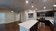 Located in the Lincoln Heights neighborhood of Houston, TX, this single-story home offers a thoughtfully designed open-concept layout that seamlessly connects the kitchen and living areas. The kitchen is a standout feature, showcasing dark espresso cabinetry, white quartz countertops, a central island, and a full suite of stainless steel appliances including a refrigerator with ice maker, electric range, built-in microwave, and dishwasher. Rich dark hardwood-style flooring runs throughout the main living areas, adding warmth and continuity to the space. The living area is spacious and airy, illuminated by recessed lighting and a ceiling fan, with a sliding glass door that opens to an outdoor area. A dedicated in-unit laundry alcove with a full-size washer and dryer adds everyday convenience. The bedrooms feature plush carpet flooring and ceiling fans, with windows that invite natural light. The primary bathroom is well-appointed with a dual-sink vanity, dark cabinetry, a large mirror, and access to a walk-in closet. A secondary bathroom offers a single vanity and a tub-shower combination. This home combines modern finishes with functional design throughout.