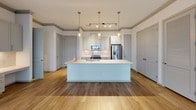 Located at 1725 W Campbell Rd in Garland, TX, this single-floor residence offers a well-designed layout with modern finishes throughout. The open-concept kitchen serves as the focal point of the living area, featuring white shaker-style cabinetry extending to the ceiling, marble-look tile backsplash, quartz countertops, and a full suite of stainless steel appliances including a range, over-the-range microwave, and French door refrigerator. A generously sized center island with an undermount sink and pendant lighting above provides both additional workspace and a natural gathering point. The kitchen flows seamlessly into the living area, which features warm wood-look flooring, a tray ceiling, and large glass doors that invite natural light and outdoor views.

The bedrooms are finished with neutral carpet and large windows framing open exterior views, with ceiling fans providing additional comfort. Bathrooms include a primary bath with granite countertops, gray cabinetry, a large framed mirror, separate glass-enclosed shower, and tile flooring. A secondary bathroom features a clean white tub-shower combination with tile surround. The overall palette of neutral tones, crown molding details, and contemporary fixtures creates a cohesive and polished living environment.