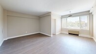 Located at 1500 Arlington Blvd in Arlington, VA, this one-bedroom, one-bathroom residence offers a thoughtfully arranged single-floor layout. The spacious bedroom features warm wood-style flooring, neutral taupe walls, clean white baseboards, and a built-in shelving ledge, creating a calm and versatile living space.

The open living area extends naturally from the bedroom, bathed in natural light through large windows fitted with horizontal blinds. A pendant light fixture adds a modern touch, while the wood-style flooring flows consistently throughout, lending cohesion to the space.

The kitchen is efficiently designed and features stainless steel appliances, including a gas range and over-the-range microwave, paired with white cabinetry and light countertops. A decorative geometric tile backsplash adds visual interest, while a bright window provides natural light and ventilation via an overhead exhaust fan.

The bathroom showcases classic white subway tile surrounding a full soaking tub and shower combination, accented by a bold black tile border along the top — a timeless design detail. A pedestal-style sink and mirrored medicine cabinet complete the clean, functional space.

A dedicated closet provides convenient storage. Overall, the residence presents a bright, move-in-ready environment with consistent modern finishes throughout.