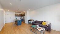 Located at 221 Monticello Ave in Williamsburg, VA, this well-appointed one-bedroom, one-bathroom unit offers a thoughtfully designed open-concept layout with modern finishes throughout. Light wood-tone flooring flows seamlessly across the entire living space, creating a bright and cohesive aesthetic.

The kitchen is a standout feature, equipped with stainless steel appliances including a refrigerator, electric range, microwave, and dishwasher. Sleek gray cabinetry with contemporary hardware pairs with a classic white subway tile backsplash and granite countertops. A central island with seating provides additional prep space and serves as a natural gathering point that connects the kitchen to the living area.

The open living room benefits from large windows that invite natural light, creating an airy atmosphere. A glass door leads to a private outdoor deck, further enhancing the sense of openness.

The bedroom is a comfortable retreat with its own sliding glass door and balcony access, allowing for natural light and outdoor views. Clean white walls and the continued wood flooring maintain the unit's modern, minimalist character.

The bathroom features tile flooring, a granite-topped vanity with gray cabinetry, and crisp white walls. A connecting hallway ties all rooms together efficiently, completing this well-organized and contemporary living space.