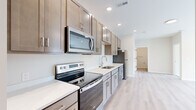 Located at 1915 S Mattis Ave in Champaign, IL, this well-appointed 2-bedroom, 1-bathroom unit offers a thoughtfully designed single-floor layout that maximizes every square foot. The open-concept kitchen and living area serves as the heart of the home, featuring a sleek galley-style kitchen outfitted with stainless steel appliances — including a range, over-the-range microwave, dishwasher, and refrigerator — complemented by warm taupe shaker cabinetry, white quartz countertops, and a single-basin sink. Light hardwood-style flooring runs throughout the main living areas, lending a bright and cohesive feel to the space. The living room receives natural light through a large window and sliding door access, creating an airy, welcoming atmosphere. Both bedrooms are finished with neutral wall tones and plush carpet, each offering a window for natural light and dedicated closet space. The bathroom is clean and modern, featuring the same light hardwood-style flooring, a glass-enclosed shower/tub area with accessibility grab bars, and a vanity with storage. Recessed lighting throughout the unit ensures consistent, well-distributed illumination. The entrance provides a convenient transition into the main living space, completing this efficiently laid-out and move-in-ready home.
