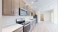 Located at 1915 S Mattis Ave in Champaign, IL, this well-appointed 2-bedroom, 1-bathroom unit offers a thoughtfully designed single-floor layout that maximizes every square foot. The open-concept kitchen and living area serves as the heart of the home, featuring a sleek galley-style kitchen outfitted with stainless steel appliances — including a range, over-the-range microwave, dishwasher, and refrigerator — complemented by warm taupe shaker cabinetry, white quartz countertops, and a single-basin sink. Light hardwood-style flooring runs throughout the main living areas, lending a bright and cohesive feel to the space. The living room receives natural light through a large window and sliding door access, creating an airy, welcoming atmosphere. Both bedrooms are finished with neutral wall tones and plush carpet, each offering a window for natural light and dedicated closet space. The bathroom is clean and modern, featuring the same light hardwood-style flooring, a glass-enclosed shower/tub area with accessibility grab bars, and a vanity with storage. Recessed lighting throughout the unit ensures consistent, well-distributed illumination. The entrance provides a convenient transition into the main living space, completing this efficiently laid-out and move-in-ready home.