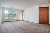 Located at 929 Harrington Dr in Madison, WI, this two-bedroom, one-bathroom single-floor home offers a well-organized and functional layout. The open-concept kitchen and living room form the heart of the space, where warm honey-toned cabinetry, stainless steel appliances — including a refrigerator, range, and dishwasher — and a breakfast bar peninsula create a practical yet inviting atmosphere. Wood-look flooring in the kitchen transitions seamlessly to plush carpeting throughout the living and bedroom areas. A ceiling fan in the living room adds comfort and airflow. Both bedrooms are carpeted and feature natural light from windows with views of surrounding greenery; the primary bedroom includes a ceiling fan, while the second bedroom offers direct patio access via a glass-panel door. The full bathroom is appointed with a wood-vanity, large mirror, tub/shower combination, and wood-look flooring. A dedicated laundry area is conveniently accessible from the kitchen. The home also boasts an impressive number of closets for generous storage throughout. A covered patio extends the living space outdoors, completing this comfortable and practical Madison residence.