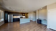Located at 9855 Federal Dr in Colorado Springs, Colorado, this two-story unit offers a well-appointed, modern interior with consistent finishes throughout. The open-concept main living area is anchored by a spacious kitchen featuring dark espresso cabinetry, granite countertops, a white subway tile backsplash, and a full suite of stainless steel appliances, including a French door refrigerator and electric range. A central island with a granite top and undermount sink provides additional prep space and is highlighted by stylish pendant lighting overhead. Wood-look luxury vinyl plank flooring extends throughout the main living areas, contributing to a clean, cohesive aesthetic.

The entry area is lined with multiple windows that draw in generous natural light and offer views of the surrounding Colorado Springs landscape. The bathroom is notably well-finished, featuring a dual-sink vanity with granite countertops, dark cabinetry with brushed nickel hardware, and a large wall-spanning mirror. Bedrooms are carpeted for comfort and include access to a spacious walk-in closet with wrap-around shelving and built-in storage. The overall ambiance is contemporary and move-in ready, with neutral tones providing a versatile backdrop throughout.