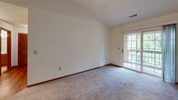 Located at 17465 W River Birch Dr in Brookfield, Wisconsin, this single-floor, 2-bedroom, 2-bathroom home offers a practical and comfortable layout with consistent finishes throughout. The living area features vaulted ceilings that enhance the sense of space, plush carpeting, and a sliding glass door that opens to an outdoor balcony, bringing in natural light and views of the surrounding greenery. A chandelier-lit dining area connects seamlessly to the kitchen via a pass-through counter, creating an open and connected feel. The kitchen is equipped with warm oak cabinetry, a double sink, a dishwasher, a refrigerator, and hardwood-style flooring that adds a clean contrast to the softer finishes elsewhere. The generously sized primary bedroom includes its own dedicated bathroom featuring a wide vanity with oak cabinetry and a well-lit mirror. The second bedroom is served by a full bathroom with a tub and shower combination. Both bedrooms are carpeted and include closets with oak sliding or hinged doors. Rich wood-toned door and window trim is carried consistently throughout the home, providing a cohesive and classic aesthetic. The overall design is clean, neutral, and move-in ready.