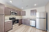 This single-floor, one-bedroom, one-bathroom unit offers a practical and modern layout across a comfortable footprint. Light-toned luxury vinyl plank flooring runs throughout every room, creating a cohesive and easy-to-maintain aesthetic.

The kitchen is a standout feature, outfitted with rich, dark-toned cabinetry, granite-look countertops, and a full suite of stainless steel appliances including a range, over-the-range microwave, dishwasher, and refrigerator. Recessed lighting illuminates the space efficiently, and the L-shaped layout maximizes both counter and storage space.

The living room is bright and open, featuring warm neutral walls, large windows that invite natural light, and a ceiling fan with lighting. The spacious bedroom also benefits from generous window placement, bathing the room in natural light and offering outdoor views.

The bathroom is cleanly finished with wood-tone cabinetry, granite-look countertops, a combined tub and shower with a curved curtain rod, and matching luxury vinyl flooring. A dedicated closet provides additional storage.

The in-unit laundry room houses a full-size washer, water heater, and HVAC unit, offering convenient all-in-one utility access. Overall, the unit presents a clean, move-in-ready environment with consistent, modern finishes throughout.