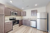 This single-floor, one-bedroom, one-bathroom unit offers a practical and modern layout across a comfortable footprint. Light-toned luxury vinyl plank flooring runs throughout every room, creating a cohesive and easy-to-maintain aesthetic.

The kitchen is a standout feature, outfitted with rich, dark-toned cabinetry, granite-look countertops, and a full suite of stainless steel appliances including a range, over-the-range microwave, dishwasher, and refrigerator. Recessed lighting illuminates the space efficiently, and the L-shaped layout maximizes both counter and storage space.

The living room is bright and open, featuring warm neutral walls, large windows that invite natural light, and a ceiling fan with lighting. The spacious bedroom also benefits from generous window placement, bathing the room in natural light and offering outdoor views.

The bathroom is cleanly finished with wood-tone cabinetry, granite-look countertops, a combined tub and shower with a curved curtain rod, and matching luxury vinyl flooring. A dedicated closet provides additional storage.

The in-unit laundry room houses a full-size washer, water heater, and HVAC unit, offering convenient all-in-one utility access. Overall, the unit presents a clean, move-in-ready environment with consistent, modern finishes throughout.