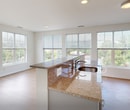 This single-floor residence in Ballston Spa, NY offers a thoughtfully designed layout across three bedrooms and two bathrooms. The open-concept kitchen and living area serves as the heart of the unit, featuring a granite-topped island with a built-in sink, gray cabinetry, stainless steel appliances, and recessed lighting overhead. Light hardwood-style flooring extends throughout the main living areas, enhancing the bright, clean aesthetic. A bank of large windows along the living room walls floods the space with natural light while offering views of the surrounding greenery and streetscape.

The three bedrooms are carpeted and finished with neutral tones, providing a calm and functional environment. The primary bedroom offers a comfortable footprint with windows overlooking the exterior. The two bathrooms are tiled, with one featuring a walk-in shower with stone-toned surround and a granite-topped vanity, and the other offering a full soaking tub with tiled surround. A central hallway connects the bedrooms to the main living area, with a closet providing additional storage. The overall design is clean, modern, and well-lit throughout.
