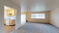 Located at 13795 SW Electric St in Beaverton, Oregon, this single-floor unit offers a practical and comfortable layout designed for everyday living. The expansive living area is finished with plush wall-to-wall carpeting and features large windows dressed with vertical blinds, allowing natural light to fill the room. A sliding glass door opens to an adjacent area, enhancing the sense of openness throughout. Warm beige tones on the walls contribute to a neutral, inviting ambiance.

The kitchen is thoughtfully designed with light wood cabinetry, granite-style countertops, and wood-look flooring. It is equipped with white appliances including a refrigerator, electric range, and dishwasher. A peninsula counter provides additional workspace and a natural separation between the kitchen and dining area.

The bedroom is generously sized, featuring soft carpet, neutral walls, and a window with vertical blinds that brings in natural light. The full bathroom includes a combined tub and shower unit, a toilet, wood-look flooring, and a vanity with granite-style countertops, warm wood cabinetry, and a large mirror. The overall layout is efficient and well-connected, making this a functional and comfortable space in a convenient Beaverton location.