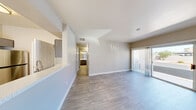 Located at 9353 W Twain Ave in Las Vegas, NV, this single-floor, 3-bedroom, 2-bathroom home offers a well-designed layout that maximizes functionality. The open-concept living room and kitchen area is anchored by light wood-look flooring and neutral-toned walls, creating a bright and cohesive atmosphere. A sliding glass door floods the living area with natural light and provides outdoor access. The galley-style kitchen is outfitted with stainless steel appliances — including a gas range, microwave, and refrigerator — complemented by sleek gray cabinetry, light stone countertops, and a modern sink fixture. The three bedrooms feature plush carpet flooring and windows with blinds that allow for natural light and outdoor views. The primary bedroom is a comfortable size and includes closet access. Two well-appointed bathrooms feature tub/shower combinations, stone-top vanities, and wood-look tile flooring. A dedicated laundry room houses a full-size washer and dryer. Additional storage is provided through two closets, including a walk-in style closet with built-in shelving and hanging rods. A hallway connects the private quarters, completing this practical and move-in-ready layout.