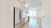 Located at 2968 W 7th St in the heart of Los Angeles, CA, this modern studio unit offers a thoughtfully designed single-floor layout that maximizes every square foot. Light hardwood-style flooring runs continuously throughout the space, lending warmth and visual continuity.

The open-concept kitchen and living area form the core of the unit. The kitchen is outfitted with a full suite of stainless steel appliances — including a refrigerator, electric range, built-in microwave, and dishwasher — complemented by sleek flat-front cabinetry in a warm neutral tone, a tile backsplash, and clean white countertops. Recessed lighting illuminates the kitchen, while the adjoining living area benefits from a large window that invites generous natural light and city views.

A dedicated walk-in closet provides practical storage with built-in wood shelving and dual hanging rods, offering well-organized space for clothing and accessories.

The bathroom features large-format neutral tile flooring, a full soaking tub with a tiled surround, a modern vanity, and recessed overhead lighting, creating a clean and calm atmosphere.

Throughout the unit, the consistent use of white walls, light flooring, and minimalist fixtures creates a bright, airy ambiance well-suited to contemporary urban living.