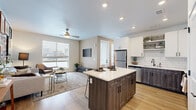 Located in Denver's vibrant 80238 neighborhood, this well-appointed one-bedroom, one-bathroom residence offers a thoughtfully designed open-concept layout with modern finishes throughout. Light-toned hardwood flooring flows seamlessly across the entire space, creating a warm and cohesive aesthetic.

The kitchen is a standout feature, showcasing two-tone cabinetry with crisp white upper cabinets and dark wood-grain lower cabinets, a classic white subway tile backsplash, stainless steel appliances, and a central island with a white quartz countertop and bar seating—ideal for both cooking and casual dining.

The kitchen opens directly into the living room, which is bathed in natural light from large windows. A ceiling fan adds comfort, and the space offers a relaxed yet stylish ambiance.

The bedroom is generously proportioned, featuring wide windows that bring in natural light, wood-look flooring, and a dedicated closet. An additional flexible area serves well as a home office or reading nook.

The bathroom is finished with a dark wood-grain vanity, white countertop, a large mirror, and warm lighting, completing the cohesive modern design palette found throughout the home.