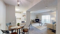 Located in Pickerington, Ohio, this 2-bedroom, 2-bathroom single-floor residence offers a thoughtfully designed layout with a warm, neutral color palette throughout. The open-concept living and dining area serves as the heart of the home, featuring plush carpeting, a tray ceiling, and a corner fireplace with a tile surround — an inviting focal point for the room. Large sliding glass doors with vertical blinds flood the space with natural light and provide access to the outdoors. The kitchen is well-equipped with white shaker cabinetry, light countertops, a double-basin sink, and a peninsula breakfast bar with pendant lighting — ideal for casual dining. Wood-look flooring grounds the kitchen area, which flows seamlessly into the dining space. The generously sized primary bedroom includes a dedicated closet and direct access to a private bathroom, which features a white vanity, a well-lit mirror, and a glass-enclosed shower. The second bedroom is bright and comfortable, with a large window offering outdoor views. A second full bathroom with similar clean finishes serves the remaining spaces. Three hallways and two closets provide ample storage and circulation throughout this efficiently organized, move-in-ready home.