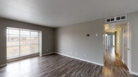 Located at 8411 Deansgate Lane in Dallas, TX, this single-story home presents a clean, updated interior with a cohesive neutral color scheme carried throughout every room. Wood-look plank flooring runs continuously across the main living areas, bedrooms, and hallways, lending a sense of warmth and visual continuity to the layout.

The living room is generously proportioned, featuring a large picture window that draws in natural light and a paneled front entry door. The open sightlines connect seamlessly to a central hallway that leads to the private areas of the home. Ceiling fans are installed in the bedrooms, contributing to year-round comfort.

The kitchen follows a galley-style configuration, offering white shaker cabinetry, granite-style countertops, a white subway tile backsplash, a stainless steel sink, and a suite of appliances including a stainless refrigerator, electric range, and built-in microwave. The bedrooms are well-sized with natural window light, ceiling fans, and closet storage.

The bathroom is finished with large-format gray wall tile surrounding a full soaking tub and shower, complemented by a white vanity with a granite-style countertop and wood-look flooring, creating a clean and functional space.