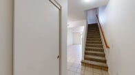 Located in Gilbert, AZ, this two-story home offers a well-organized layout across two floors. The main level features light tile flooring throughout and hosts the combined living, dining, and kitchen area. The kitchen is equipped with warm wood cabinetry, dark granite-style countertops, black appliances including a refrigerator, electric range, microwave, and dishwasher, along with a double sink and a window that brings in natural light. The open dining and living areas connect seamlessly, with a sliding glass door leading to a private patio with neighborhood views. A carpeted staircase with a wood handrail leads to the upper level. The three bedrooms are located upstairs, each featuring plush carpet flooring, ceiling fans with light fixtures, and windows fitted with vertical blinds. The primary bedroom offers a generous footprint with ample closet space. Two full bathrooms serve the home — one featuring wood-look flooring, a single vanity, toilet, and a tub/shower combo. Additional highlights include multiple closets throughout, a dedicated laundry area, and a clean, neutral color palette that provides a bright, move-in-ready atmosphere throughout the home.