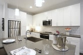 Located in Sandy Springs, GA, this single-floor residence offers a thoughtfully designed layout that balances modern style with everyday functionality. The open-concept kitchen is a standout feature, showcasing crisp white shaker cabinetry, grey quartz countertops, a classic subway tile backsplash, and a full suite of stainless steel appliances including a refrigerator, gas range, microwave, and dishwasher. Wood-look flooring runs throughout, tying the space together with warmth and cohesion. The living area is bright and welcoming, with large French doors that invite an abundance of natural light and offer views of the surrounding greenery. A ceiling fan adds comfort, while the neutral palette creates a versatile backdrop for any décor. The bedroom is a serene retreat, featuring large windows with tree-lined views, plush carpeting, and soft, neutral tones that foster a calm atmosphere. The en-suite bathroom is well-appointed with wood-look flooring, a soaking tub with shower, and direct access to a generously sized walk-in closet complete with built-in shelving and hanging storage. Throughout the residence, clean architectural lines and a cohesive design language create an inviting and polished living environment.