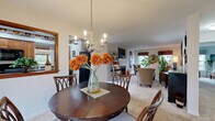 Located at Merchant's Square in Lancaster, PA, this well-designed single-floor residence offers a comfortable and functional layout across a thoughtfully arranged floor plan. The welcoming entrance opens into a spacious living room featuring plush carpeting, large windows that invite natural light, and ample room for relaxed seating arrangements. The adjoining dining area flows seamlessly from the living room and is anchored by an elegant chandelier overhead, creating an inviting space for meals and gatherings. A pass-through window connects the dining area to the kitchen, which features warm honey-toned wood cabinetry, dark granite-style countertops, a double stainless steel sink, and black appliances including a range and built-in microwave. A dedicated office provides a quiet retreat with large windows overlooking outdoor greenery, offering an ideal work-from-home environment. The generously sized primary bedroom is bathed in natural light from a large window and features soft carpeting and a calm, restful ambiance. A walk-in closet with built-in shelving and hanging rods provides excellent storage. The full bathroom is finished with tile flooring, a wood-toned vanity with a white countertop, and a shower-tub combination. Throughout, the residence presents a cohesive, neutral palette that is both timeless and versatile.