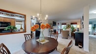 Located at Merchant's Square in Lancaster, PA, this well-designed single-floor residence offers a comfortable and functional layout across a thoughtfully arranged floor plan. The welcoming entrance opens into a spacious living room featuring plush carpeting, large windows that invite natural light, and ample room for relaxed seating arrangements. The adjoining dining area flows seamlessly from the living room and is anchored by an elegant chandelier overhead, creating an inviting space for meals and gatherings. A pass-through window connects the dining area to the kitchen, which features warm honey-toned wood cabinetry, dark granite-style countertops, a double stainless steel sink, and black appliances including a range and built-in microwave. A dedicated office provides a quiet retreat with large windows overlooking outdoor greenery, offering an ideal work-from-home environment. The generously sized primary bedroom is bathed in natural light from a large window and features soft carpeting and a calm, restful ambiance. A walk-in closet with built-in shelving and hanging rods provides excellent storage. The full bathroom is finished with tile flooring, a wood-toned vanity with a white countertop, and a shower-tub combination. Throughout, the residence presents a cohesive, neutral palette that is both timeless and versatile.