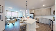 This 2-bedroom, 2-bathroom residence combines contemporary design with functional living across a single, well-planned floor. The open-concept kitchen serves as the heart of the home, featuring light wood cabinetry, a full suite of stainless steel appliances, white quartz countertops, and a generously sized curved island with bar seating — ideal for casual dining or entertaining. Rich hardwood-style flooring flows throughout the main living areas, adding warmth and cohesion to the space.

The living and dining areas are bathed in natural light through large windows with outdoor views, creating a bright and inviting atmosphere. The dining area comfortably accommodates a dining set, while the living room offers ample space for relaxed seating arrangements.

Both bedrooms are carpeted and feature ceiling fans, ample closet space, and access to natural light. The primary bedroom includes a walk-in closet and an en-suite bathroom, while the second bedroom is served by a well-appointed full bathroom featuring a soaking tub with tiled surround, wood-look flooring, and light cabinetry with quartz countertops. A dedicated laundry area and additional storage further enhance the practicality of this thoughtfully designed residence.