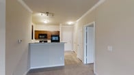 This well-designed 2-bedroom, 2-bathroom residence with a sunroom offers a comfortable and functional single-floor layout. The open-concept kitchen features rich dark wood cabinetry, black appliances including a built-in microwave and range, and a granite-topped breakfast bar that provides additional seating and separates the kitchen from the living area. Crown molding accents the ceilings throughout, adding a refined architectural touch, while neutral-toned walls and a mix of tile and carpet flooring create a cohesive and welcoming atmosphere. Track lighting in the kitchen area ensures ample illumination, complemented by flush-mount fixtures in the adjoining spaces. The hallway leads to multiple rooms, with bi-fold and panel doors providing access to the bedrooms, bathrooms, and additional storage. The inclusion of a sunroom adds a distinctive bonus space, ideal for relaxing or working, with the potential for natural light. Overall, the residence offers a clean, practical layout with classic design details that make it a comfortable and move-in-ready home.