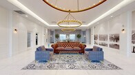 The lobby at 620 Amelia St in Fredericksburg, Virginia, presents a polished and sophisticated first impression through its thoughtfully designed interior. The space is generously proportioned, with a coffered ceiling detail framing a pair of large, gold-toned ring chandeliers that serve as the room's focal point, casting a warm, ambient glow throughout. Recessed lighting further brightens the white walls and ceilings, contributing to the open, airy atmosphere.

The flooring throughout is finished in large-format marble-look tile, lending a clean and refined aesthetic. At the heart of the lobby, a curated seating arrangement features tufted Chesterfield leather sofas paired with channel-tufted upholstered armchairs in muted blue-grey tones, all anchored by an ornate patterned area rug and a gold-accented glass coffee table.

Along the back wall, stainless steel elevator banks are flanked by potted trees, adding a natural element to the space. Black-and-white photographic murals of local Fredericksburg scenery line the walls, offering a nod to the building's historic surroundings. Arched floor-to-ceiling windows and glass entry doors flood the space with natural light while providing views of the streetscape outside.