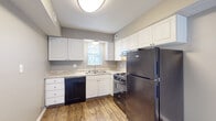 Located at 5028 Dierker Rd in Columbus, Ohio, this two-floor residence offers a well-organized layout across both levels. The kitchen is equipped with white shaker-style cabinetry, light granite-look countertops, a double-basin sink, and stainless steel appliances including a gas range and refrigerator, complemented by a black dishwasher and durable hardwood-style vinyl flooring. Natural light filters in through a window fitted with blinds. The main living area features the same hardwood-style flooring and a large sliding glass door with vertical blinds that opens to an outdoor space, filling the room with ample natural light. A carpeted staircase with a wood and metal railing connects the two floors. The bedrooms are finished with plush carpeting and neutral-toned walls; one bedroom features dual windows for added brightness, while another includes built-in shelving, hardwood-style flooring, and convenient storage. The bathroom is outfitted with a full tub and shower surround with integrated shelving, brushed nickel fixtures, and matching hardwood-style flooring. Throughout the home, a consistent neutral color palette and clean finishes create a cohesive and functional living environment.