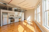 Located in the heart of Atlanta, GA (30303), this single-floor loft showcases a compelling blend of industrial character and modern convenience. The space is defined by its striking exposed wood beam ceilings with visible ductwork, lending an authentic warehouse-style aesthetic throughout.

The main living area is bathed in natural light, courtesy of large windows and glass French doors that open to an outdoor terrace with direct views of the surrounding downtown Atlanta skyline. Warm, wide-plank hardwood floors extend throughout, complementing the raw, textured walls and soaring ceiling height.

The kitchen is thoughtfully equipped with white cabinetry offering generous storage, dark granite-style countertops, a stainless steel sink, and black appliances including a gas range, dishwasher, and refrigerator. Recessed lighting illuminates the workspace efficiently.

The bathroom presents a clean, functional design with wood-tone flooring, a combined shower and bathtub with a rain-style showerhead, a white toilet, and a wide vanity topped with dark stone counters and a large mirror, providing ample grooming space.

Overall, this loft delivers a distinctive urban living experience, combining the raw charm of exposed structural elements with practical modern finishes — all set within one of Atlanta's most central and vibrant downtown locations.