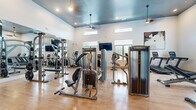 Located at 3 Lexington Ct in Merrimack, New Hampshire, this fitness center is a thoughtfully designed, single-floor facility built to support a comprehensive workout experience. The space is defined by its soaring ceilings, which lend an open and airy atmosphere throughout. A striking teal-painted ceiling accent adds a modern, stylish touch to the interior, complemented by warm hardwood-style flooring that runs across the entire facility.

Natural light pours in through a series of large, well-positioned windows along the perimeter walls, creating a bright and energizing environment. Wall-mounted flat-screen televisions and ceiling-mounted pendant and fan fixtures further enhance the functional comfort of the space.

The fitness center is outfitted with an extensive selection of Matrix-brand equipment, including cable machines, multi-station strength units, treadmills, ellipticals, recumbent bikes, and upright cycles. A dedicated free weights area features a full rack of dumbbells alongside adjustable benches, catering to a wide range of strength training needs.

Floor-to-ceiling mirrors line portions of the walls, expanding the sense of space and allowing users to monitor their form during workouts. A decorative slatted wood ceiling element adds an architectural focal point, separating distinct zones within the gym. The overall ambiance is clean, modern, and professional.