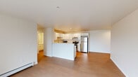 This single-floor residence offers a thoughtfully designed layout across a comfortable footprint, accommodating two bedrooms, two bathrooms, and a dedicated laundry room. The open-concept living and kitchen area forms the heart of the unit, where light wood-style flooring flows throughout. The kitchen is well-equipped with white shaker cabinetry, marble-look countertops, stainless steel appliances including an electric range, microwave, and refrigerator, and a peninsula that provides additional prep space and separates the kitchen from the living area. Recessed lighting illuminates the space effectively.

The living area features a sliding glass door that invites natural light and provides outdoor access. Both bedrooms are carpeted and include wall-mounted climate control units and natural light from windows. The primary bedroom offers a spacious closet with bifold doors. The two bathrooms are finished in neutral tones with wood-style flooring; one includes a shower-tub combination, while the other features a walk-in shower stall with a white vanity. The dedicated laundry room accommodates a full-size washer and dryer with overhead shelving for added storage.