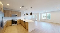 Located at 1095 Union St in Spartanburg, SC, this well-appointed single-story unit offers a thoughtfully designed open-concept layout. The combined kitchen and living area serves as the heart of the home, featuring warm natural wood cabinetry, crisp white quartz countertops, a central island with an undermount sink, and stainless steel appliances including a refrigerator, range, microwave, and dishwasher. Three stylish black pendant lights hang above the island, complementing the modern aesthetic. Light hardwood-style flooring runs throughout, enhancing the bright, airy feel. The spacious living area is lined with multiple windows and a glass-panel exterior door, inviting generous natural light and outdoor views. The bedroom is a comfortable, well-sized retreat with a ceiling fan, hardwood-style flooring, and dual windows that further brighten the space. The bathroom features a wide wood-toned vanity, white quartz countertop, a framed mirror, contemporary lighting, and a tiled shower. Three closets, including a walk-in with wire shelving, provide ample storage, while a dedicated laundry area adds everyday convenience. Clean white walls and a consistent modern palette create a cohesive, move-in-ready environment throughout.