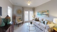 This single-floor residence offers a thoughtfully designed layout that balances comfort and functionality. The welcoming entryway, finished with light wood-look flooring, leads directly into the heart of the home. The kitchen features white cabinetry, dark countertops, black appliances, and a peninsula with a double sink that opens to the dining area — an ideal setup for everyday living and entertaining. Crown molding adds a refined touch to the kitchen and adjoining spaces. The dining area is accented by light wood-look flooring, framed wall mirrors, and vibrant artwork, creating an inviting atmosphere for meals. The living room is bright and airy, benefiting from natural light through large windows and sliding glass doors. Crown molding, light wood-look flooring, and tasteful décor complete the space. The primary bedroom features plush carpeting, a ceiling fan, and a generous window, while the second bedroom mirrors the same comfortable aesthetic. Both bathrooms are well-appointed with dark countertop vanities, light wood-look flooring, and ample storage. The second bathroom includes an extended vanity and a shower with curtain enclosure. Throughout the residence, a neutral color palette and consistent finishes create a cohesive, modern ambiance.