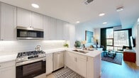 Located in the heart of Buckhead at 340 E Paces Ferry Rd NE, Atlanta, this thoughtfully designed one-bedroom, one-bathroom residence offers a refined urban living experience. The open-concept kitchen and living area form the heart of the home, where light wood-tone flooring flows seamlessly throughout. The kitchen is outfitted with stainless steel appliances, including a gas range, built-in microwave, and French door refrigerator, complemented by sleek gray cabinetry extending to the ceiling, white quartz countertops, a subway tile backsplash, and a peninsula with bar seating for two. The living area is anchored by a large floor-to-ceiling window framing sweeping city views, filling the space with natural light. A textured geometric wallcovering adds warmth and visual interest to the living room walls. The bedroom features a dramatic accent wall with a richly textured wallcovering, a large window with city views, and light wood flooring. The bathroom is finished with large-format light tile, a glass-enclosed walk-in shower, and a clean white vanity with an integrated sink. A dedicated closet provides practical storage. This residence combines contemporary design with elevated finishes in one of Atlanta's most sought-after neighborhoods.