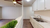 Located at 7800 Woodman Ave in the Panorama City neighborhood of Los Angeles, this single-floor unit offers a practical and comfortable layout with consistent wood-style flooring throughout. The living area is open and well-lit, benefiting from a large window dressed with vertical blinds that allow natural light to fill the space. A textured ceiling and a ceiling fan add character to the room while maintaining a functional atmosphere.

The kitchen is designed with an open pass-through concept, featuring a speckled laminate countertop that extends as a breakfast bar, white cabinetry providing ample storage, a double-basin sink, and a gas range. A ceiling fan with a light fixture keeps the kitchen area comfortable and airy. The kitchen flows seamlessly into the living space, making it ideal for everyday use.

The bathroom is clean and functional, appointed with a wide vanity topped with a granite-style countertop, a large mirror, wood-toned cabinetry below, and a tiled shower-tub combination. Grab bars and a towel rack are also present, adding practicality to the space.

A separate room features rich, dark wood-style flooring, a large window with vertical blinds, and a textured ceiling, offering a versatile space suitable as a bedroom or home office. A wall-mounted heater unit provides additional climate control. The overall ambiance of the unit is clean, neutral, and move-in ready.
