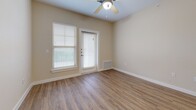 Located at 960 Merrill Dr in Leander, TX, this well-appointed one-bedroom, one-bathroom unit offers a functional and comfortable single-floor layout. The open-concept living and kitchen area is anchored by warm wood-look flooring and neutral warm-beige walls that create a bright, welcoming atmosphere. The kitchen is equipped with white shaker-style cabinetry, granite-look countertops, and a full suite of black appliances including a refrigerator, gas range, microwave, and dishwasher. Pendant lighting and a track light fixture add a modern touch above the kitchen peninsula, which doubles as a breakfast bar.

The living area benefits from natural light through windows fitted with blinds, and features a ceiling fan for added comfort. A private entry door with an adjacent window further enhances natural light in the space. The bedroom is generously proportioned, finished with plush carpet, a ceiling fan, and a window with an outdoor view. It connects directly to a walk-in closet, offering ample storage. The bathroom continues the home's clean aesthetic with white cabinetry, granite-look countertops, wood-look flooring, and a tiled shower. A hallway connects the main living spaces, completing this efficiently designed and move-in-ready home.