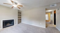 Located at 3924 Calibre Bend Lane in Winter Park, Florida, this single-floor, 2-bedroom, 2-bathroom residence offers a well-organized layout designed for comfortable everyday living. The living room serves as the centerpiece of the home, highlighted by a wood-burning fireplace flanked by built-in shelving on both sides — ideal for display or storage. Plush carpeting, a ceiling fan with light fixture, and a textured ceiling complete the relaxed atmosphere of this main gathering space. The kitchen features warm-toned wood cabinetry, granite-style laminate countertops, tile flooring, and a black range, providing a practical and efficient cooking environment. Both bedrooms are carpeted and offer generous closet space, including a walk-in closet in one room and a bifold-door closet in the other. The two bathrooms are consistently appointed with tile flooring, wood vanities with stone-style countertops, large mirrors, and tub-shower combinations with white tile surrounds. A hallway connects the private sleeping quarters to the rest of the home. Neutral tones and consistent finishes throughout give the space a cohesive, move-in-ready feel.