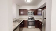 Located at 40 Clermont Xing Ct in Maryland Heights, Missouri, this single-floor unit offers a clean, contemporary design with consistent wood-look flooring extending throughout the living areas, bedrooms, and hallways. The kitchen is well-appointed with rich dark-espresso cabinetry, light granite-style countertops, and a full suite of stainless steel appliances, including a range, over-the-range microwave, refrigerator, and dishwasher. A peninsula-style counter with pendant lighting connects the kitchen to the main living area, creating an open and functional flow.

The living area is bright and open, featuring a door with a window that allows natural light to filter in. Multiple bedrooms feature windows with views of surrounding greenery, maintaining a light and airy atmosphere. White walls throughout contribute to a clean, neutral aesthetic.

The bathrooms are well-designed, with one featuring a full soaking tub and shower combination with a dark wood vanity, and another offering a dedicated walk-in shower. The overall layout, as visible in the floor plan, is thoughtfully organized to maximize flow between the kitchen, living, and private spaces.