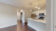Located at 5761 Fenimore Trail Dr W in Columbus, Ohio, this single-floor residence offers three bedrooms, two bathrooms, and a thoughtfully arranged layout. The open-concept kitchen serves as a focal point, showcasing a large island with a striking marble-look countertop, an undermount sink, and pendant lighting overhead. White shaker cabinetry reaches toward the ceiling, complemented by stainless steel appliances including a refrigerator, range, and microwave. Rich, dark hardwood-style flooring extends throughout the main living areas, adding warmth and visual continuity. The living room receives generous natural light through a large window and glass door, creating a bright and welcoming atmosphere. Each bedroom is finished with plush carpet and features windows that bring in additional daylight. The primary bedroom offers a comfortable, well-proportioned retreat. Both bathrooms are finished with marble-look vanity countertops, white cabinetry, and dark hardwood-style flooring. The full bathroom includes a tub/shower combo with a curved curtain rod and built-in shelving. Neutral, warm-toned walls throughout the home provide a clean, move-in ready canvas. A hallway and dedicated closet complete the functional layout of this well-appointed Columbus residence.