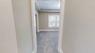 Unit 10 at 3845 Riveredge Rd in Cleveland, Ohio offers a practical single-floor layout spanning 740 square feet, accommodating four bedrooms and one bathroom. The bedrooms are finished with soft gray carpeting and neutral warm-beige walls, with several rooms featuring elegant crown molding and modern flush-mount light fixtures. The spacious primary bedroom measures 240 square feet and includes a triple-pane window that invites abundant natural light and outdoor views. Additional bedrooms are similarly carpeted and windowed, providing bright and versatile spaces. Connected hallways provide smooth circulation throughout the unit. The kitchen is equipped with stainless steel appliances including a full-size refrigerator, gas range, and over-the-range microwave, complemented by white shaker-style cabinetry, a subway tile backsplash, and light hardwood-style flooring. The bathroom features a soaking tub framed by large-format marble-patterned wall tiles and a natural light window, lending a clean, updated aesthetic. White baseboard trim runs consistently throughout the unit, reinforcing a cohesive and well-maintained interior. This unit offers a functional and refreshed living environment in a residential Cleveland neighborhood.