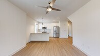 This well-appointed single-story home offers three bedrooms, two bathrooms, and a thoughtfully designed layout that maximizes comfort and functionality. The open-concept living and kitchen area serves as the heart of the home, featuring light wood-tone flooring, crisp white walls, and abundant natural light from large windows with blinds. A ceiling fan anchors the living space, while pendant lighting adds a modern touch above the kitchen island. The kitchen is outfitted with white shaker-style cabinetry, a subway tile backsplash, stainless steel appliances including a French door refrigerator, and recessed lighting overhead. The bedrooms offer plush carpeting and generous natural light, with windows framing views of surrounding greenery. The primary bedroom connects to a well-designed en-suite bathroom featuring a long white vanity with a quartz-style countertop, a framed mirror, brushed nickel hardware, wood-look flooring, and a marble-tile walk-in shower. Each bedroom is served by its own closet, including a walk-in closet with wire shelving for organized storage. A hallway connects the private spaces, and the overall aesthetic throughout is clean, modern, and move-in ready.
