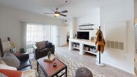 This single-floor residence offers a well-organized layout that balances communal and private living spaces. The open-concept living area is anchored by light wood-style flooring, a ceiling fan, and a sliding glass door that invites natural light and provides patio access. A built-in media console and neutral walls create a clean, versatile backdrop for the space.

The kitchen features rich dark cabinetry, light stone-look countertops, and a peninsula with bar seating for two, making it both functional and social. An adjacent dining area provides additional seating, completing the connected layout.

Multiple bedrooms are found throughout the unit, each with carpet or wood-style flooring, and windows that allow natural light. The rooms vary in character, with one featuring a bold red accent wall and another with a softer, neutral palette.

The bathrooms are thoughtfully designed, with rich dark wood vanities, dual sinks, large mirrors with strip lighting, and separate water closets housing tub and shower combinations. Light wood-style flooring ties the bathrooms cohesively to the rest of the residence.

Overall, the space presents a practical and comfortable layout suited for shared or individual living.