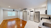 Located in the sought-after Peachtree Hills neighborhood of Atlanta, GA, this thoughtfully designed unit offers an efficient and modern living experience. The open living area features warm hardwood floors and neutral gray walls, creating a bright and welcoming atmosphere. A ceiling fan with recessed lighting overhead adds both comfort and style to the space.

The kitchen is a standout feature, outfitted with white shaker cabinetry extending to the ceiling, stainless steel appliances including a gas range, built-in microwave, dishwasher, and refrigerator, complemented by granite countertops and a classic subway tile backsplash. Marble-look porcelain tile flooring flows seamlessly through the kitchen and utility area, providing a clean and cohesive aesthetic.

A stacked washer and dryer unit is conveniently integrated into the main living space, alongside a wall-mounted mini-split HVAC system for efficient climate control. The bathroom is elegantly appointed with marble-look tile throughout, a granite-topped vanity with white cabinetry, a tub-shower combination, and a natural light-admitting window. A dedicated closet provides additional storage. This unit combines functional design with modern finishes in a prime Atlanta location.