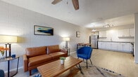 This single-floor residence offers a thoughtfully designed open-concept layout that seamlessly connects the living, dining, and kitchen areas into one cohesive, functional space. The living area is anchored by a painted brick accent wall that adds texture and character, complemented by light wood-style flooring, a ceiling fan, and a textured ceiling. Natural light filters in through a front-facing window, creating a bright and welcoming atmosphere.

The kitchen is well-equipped with stainless steel appliances, including a refrigerator, electric range, and over-the-range microwave. White shaker-style cabinetry, gray countertops, and a white subway tile backsplash give the kitchen a clean, modern aesthetic. A pendant light and track lighting provide ample illumination.

The dining area sits adjacent to the kitchen, offering a natural flow for everyday living and entertaining. The bathroom features a white vanity with gray countertop, modern hardware, and wood-look tile flooring for a polished, contemporary feel.

Both bedrooms are comfortably sized, each featuring the same light wood-style flooring, textured ceilings, and windows that allow natural light in. One bedroom showcases a painted brick accent wall, adding a distinctive design element consistent with the rest of the unit.