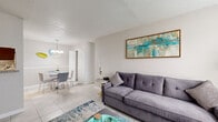 This single-story home offers a practical and comfortable layout across three bedrooms, one bathroom, a living room, two dining areas, and a kitchen, all connected by a central hallway. Light-toned tile flooring runs throughout, lending a clean and cohesive feel to the entire space.

The living room serves as the heart of the home, featuring a large window that fills the room with natural light. A textured ceiling adds character, while the open sightline connects seamlessly to the adjacent dining area, which is accented by a pendant chandelier.

The galley-style kitchen is efficiently designed with dark cabinetry, granite-look countertops, a stone tile backsplash, and white appliances, including a range and refrigerator. A second dining space provides additional flexibility for meals or gatherings.

The spacious primary bedroom offers generous proportions, while the two secondary bedrooms each feature windows that invite natural light and provide comfortable, functional spaces. A walk-in closet with built-in shelving provides ample storage. The shared bathroom is well-appointed with a granite vanity, a combined tub and shower, and tile flooring.

Overall, the home presents a bright, neutral palette with consistent finishes that create a welcoming and functional living environment.