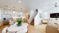 This two-story residence in Albuquerque, NM offers a thoughtfully designed layout across two floors, with the main level hosting an open-concept living, dining, and kitchen area alongside a garage and half bath, while the upper level accommodates all three bedrooms and additional bathrooms. The kitchen is a standout feature, showcasing crisp white cabinetry, stainless steel appliances, a central island with bar seating, and globe pendant lighting over light wood-tone flooring that flows throughout the main level. The adjoining dining area is bright and airy, benefiting from natural light through slatted blinds. The living room offers an open, relaxed atmosphere with soaring angled ceilings and a staircase that adds architectural interest. Each bedroom is well-proportioned, with the primary suite featuring its own closet and an en-suite bathroom. Secondary bedrooms are bright with large windows. The four bathrooms are clean and modern, finished in a consistent light palette. Additional highlights include a dedicated laundry room with full-size washer and dryer, four closets for ample storage, and an attached garage offering convenience and extra space. The overall aesthetic is cohesive—light, neutral, and modern throughout.